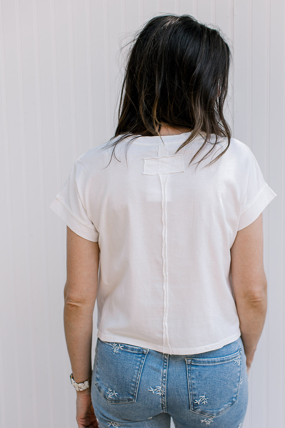 Back view of Model wearing a white, crew neck tee with an extended shoulder short sleeves. 