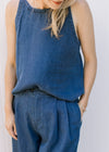 Close up of pleating detail, pockets and button closure on the pants of a matching set. 