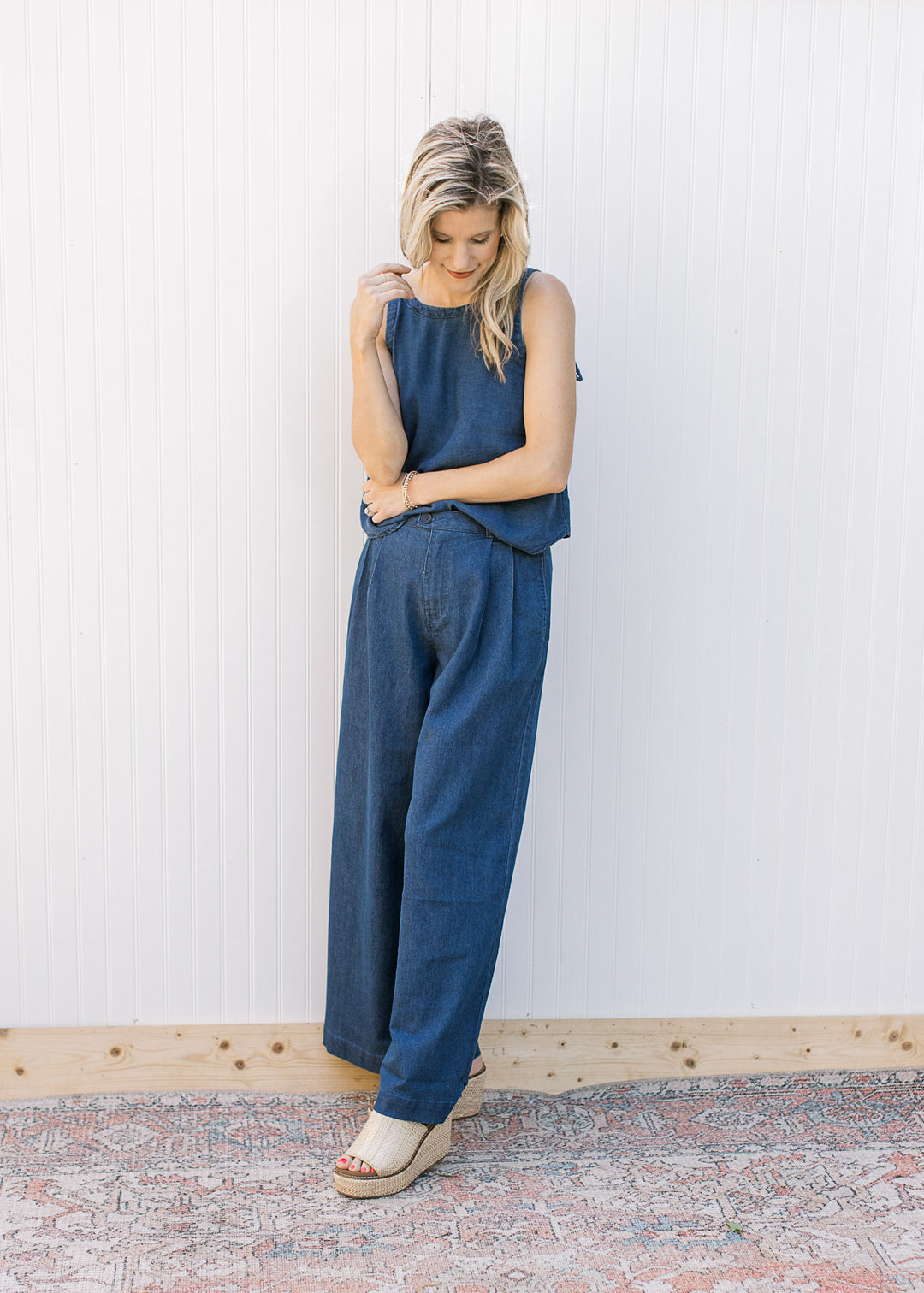Model wearing a denim blue set with a spaghetti strap top with faux tie and wide legs bottoms.