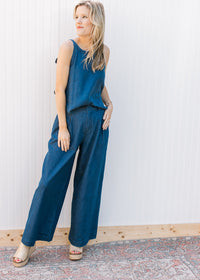 Model wearing sandals and a denim blue set with a spaghetti strap top wide legs bottoms.
