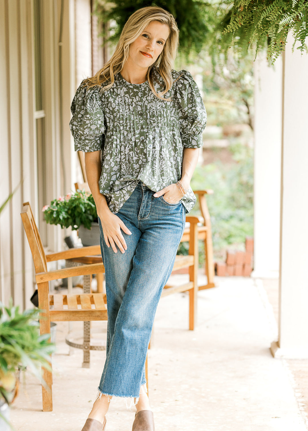 Model wearing jeans and an olive top with a blue print, micro pleat bodice and short puff sleeves. 