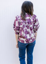 Back view of Model wearing a cream v-neck top with plum floral, ric-rac detail and 3/4 sleeves. 