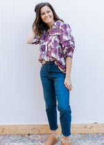 Model wearing jeans, mules and a cream v-neck top with plum floral and 3/4 sleeves. 