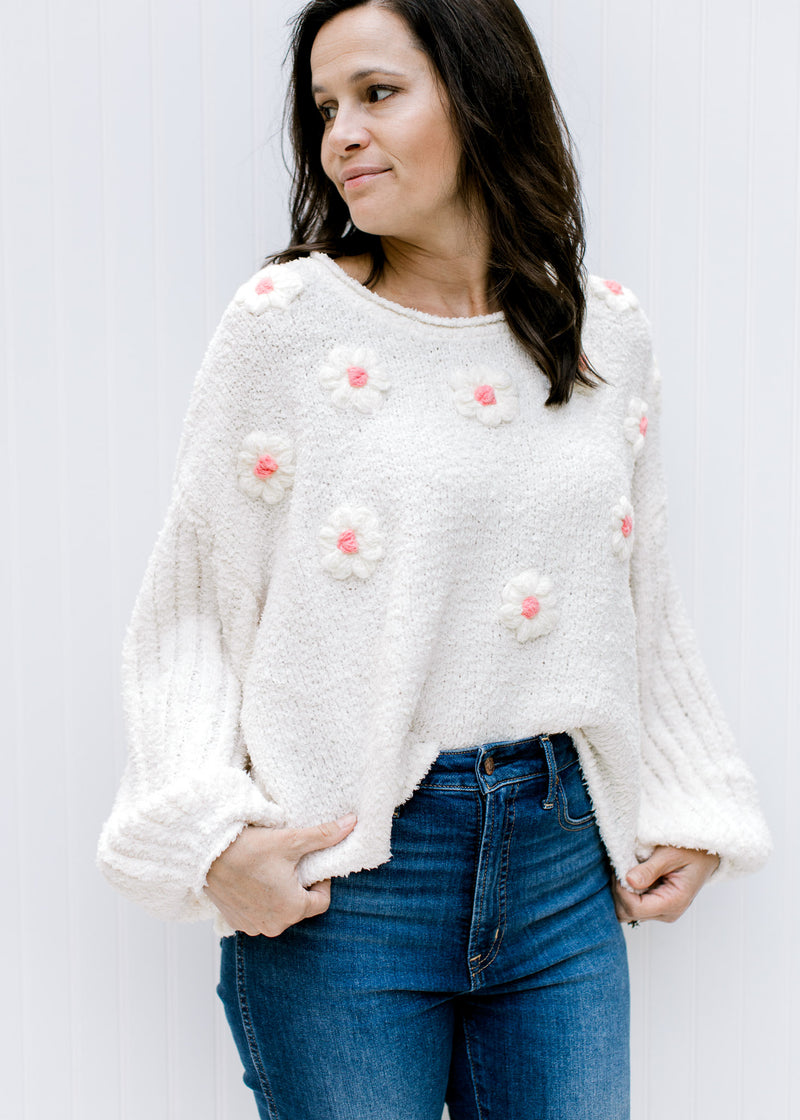 Model wearing an ivory sweater with textured flowers, ribbed bubble long sleeves and rolled hem.  