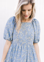 Close up of square neckline and bubble short sleeves on a pale blue midi with white poppy flowers.