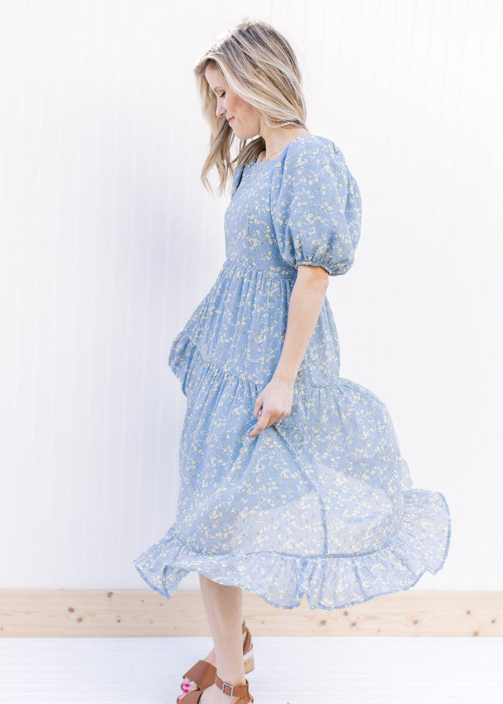 Side view of Model wearing a baby blue dress with white poppy flowers and bubble short sleeves.