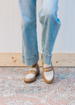 Front view of a model wearing taupe and almond loafers with a flat block heel and coin detail. 