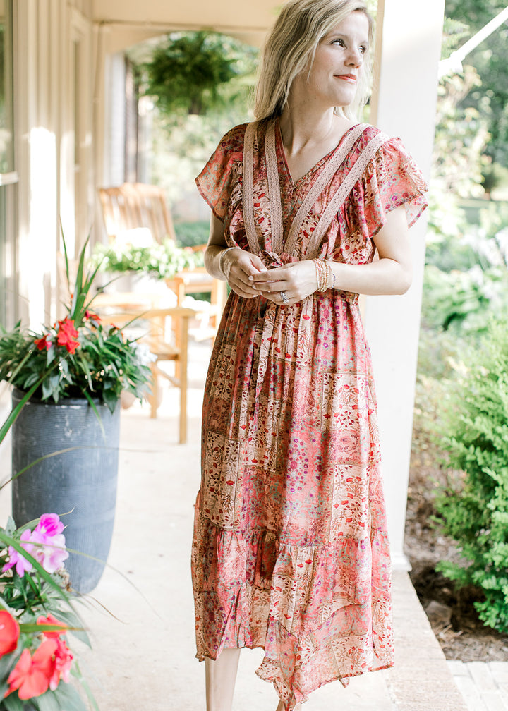 Model wearing a maroon midi with patches, floral hues, v-neck and flutter short sleeves.