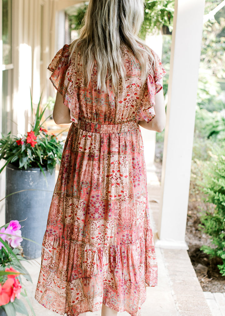 Back view of Model wearing a maroon midi with floral patches, and flutter short sleeves.