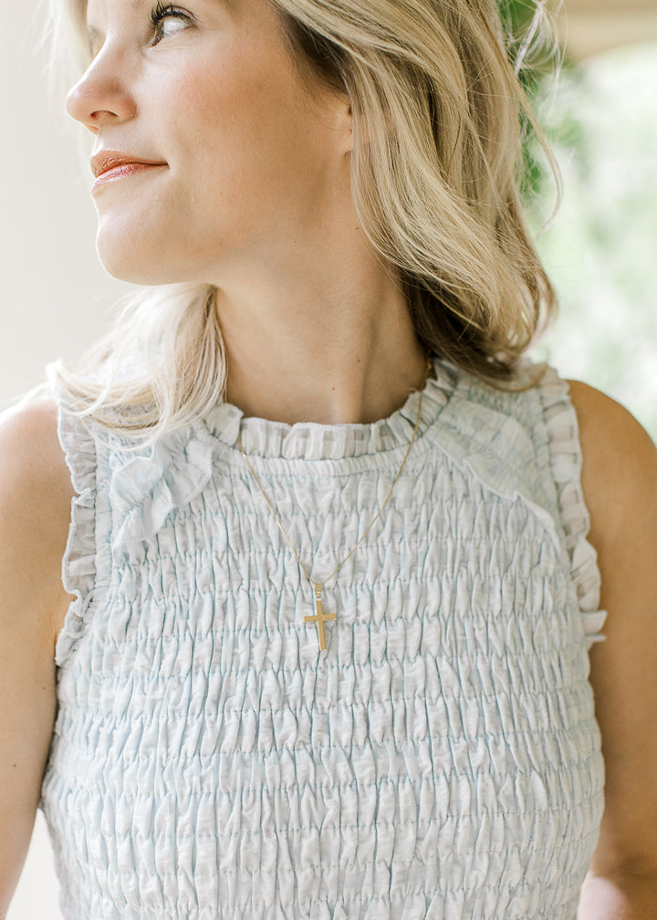 Close up of ruffles at sleeve and neck and smocked bodice on a powder blue midi with checks. 
