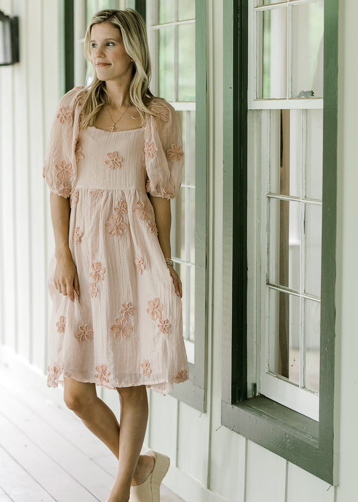 Model wearing a light pink above the knee dress with elastic at waist and bubble short sleeves. 