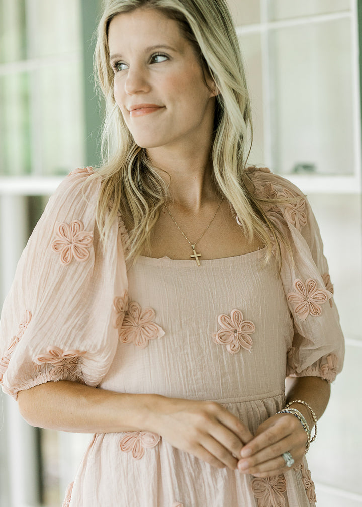 Close up of textured tulle flowers on a light pink dress with bubble short sleeves and square neck. 