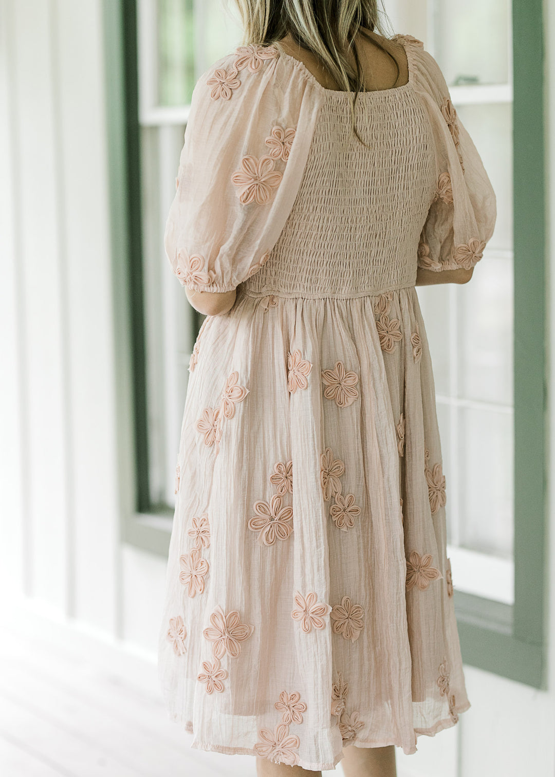 Back view of Model wearing a light pink dress with smocked back and bubble short sleeves. 