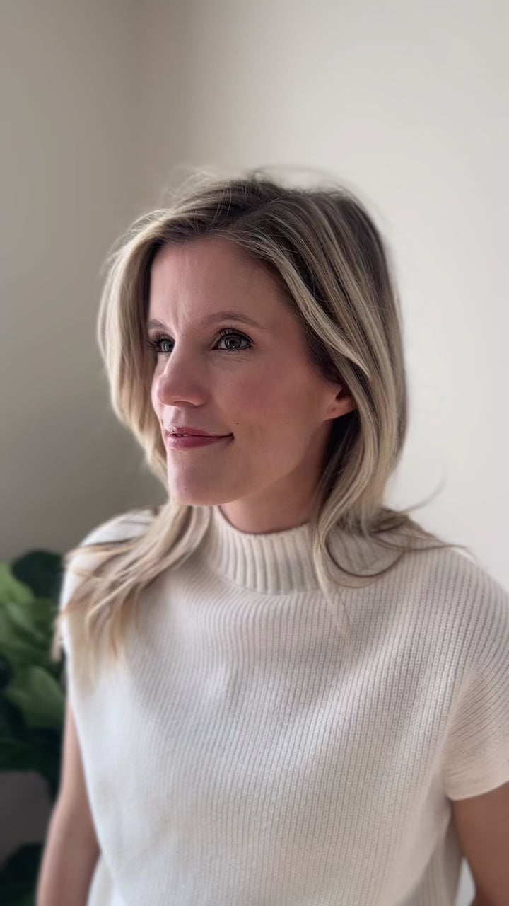 Video of Model wearing a creamy knit top with a ribbed mock neck and hem and short drop sleeves. 