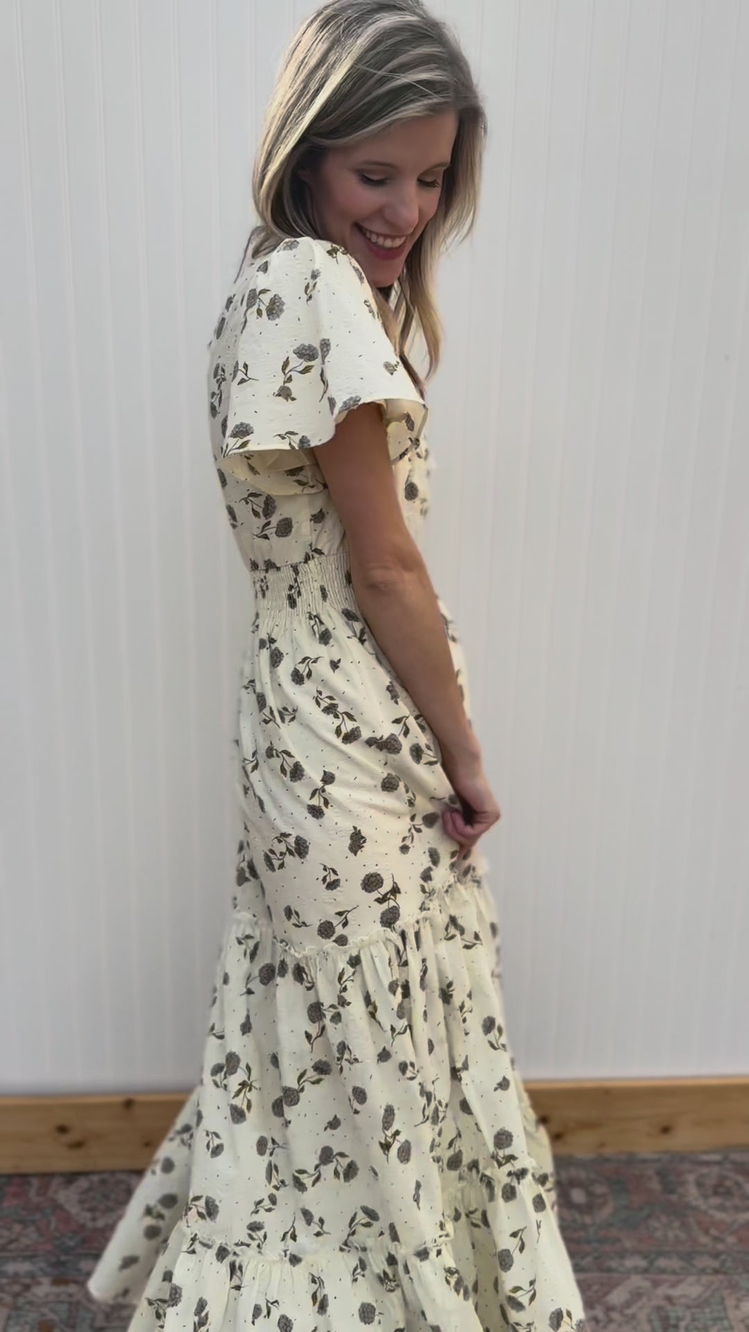 Video of Model wearing a cream v-neck maxi with hydrangea print, flutter short sleeves and elastic waist.