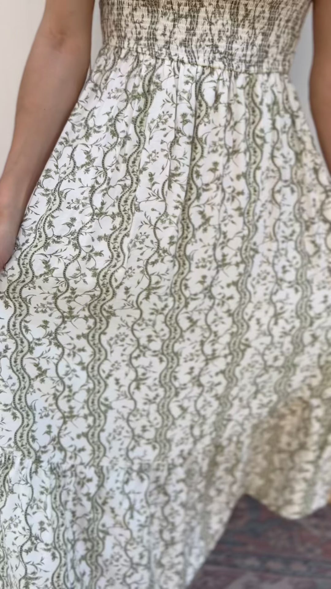 Video of Model wearing an off-white midi with climbing olive floral, square neck and smocked bodice.