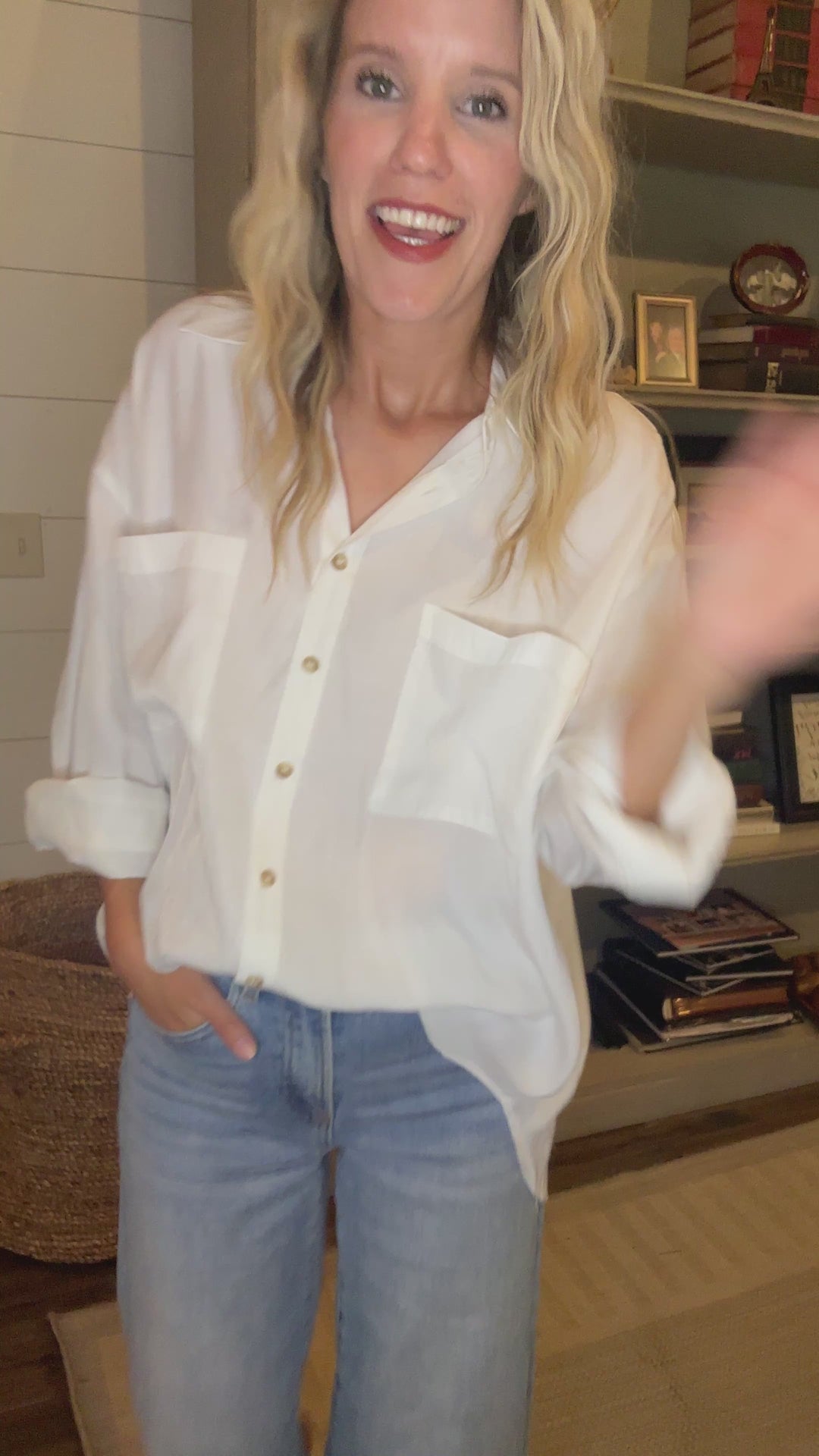 Video of Model wearing a bright white button up top with double patch pockets and long sleeves. 