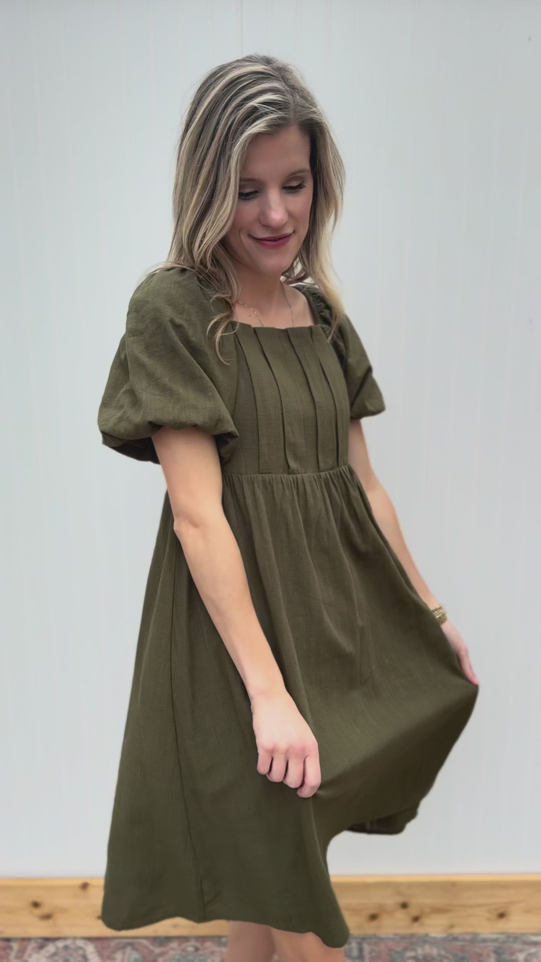 Video of Model wearing a textured olive knee length dress with a square neck and short sleeves.