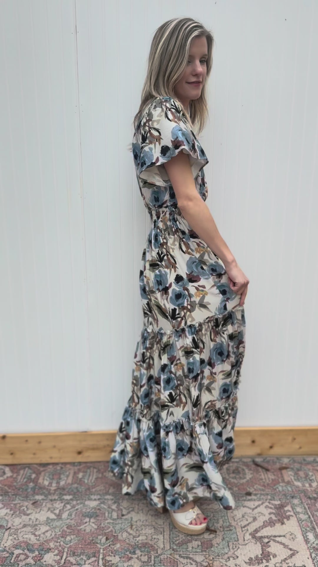 Video of Model wearing a cream v-neck maxi with watercolor floral, flutter short and elastic waist. 