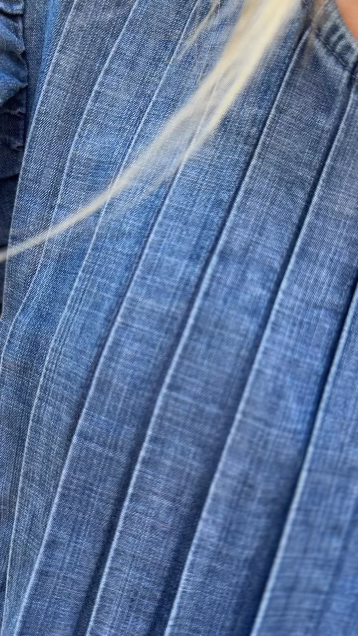 Video of Model wearing a medium/dark denim top with flutter cap sleeves, and pleated design.