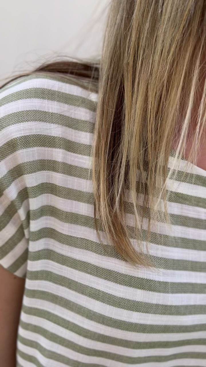 Video of an olive green and white stripe set, top has a cropped fit and boat neck with a midi skirt.