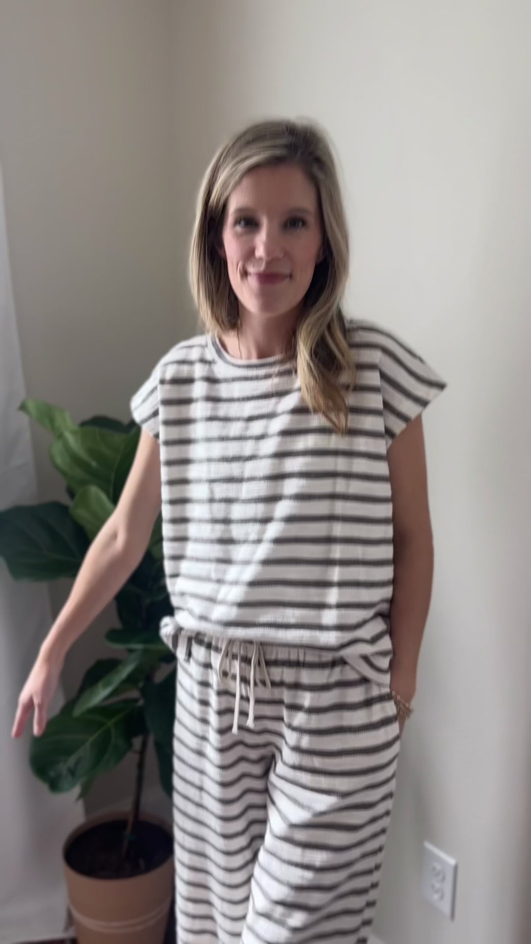 Video of Model wearing a gran and white lounge set with a short sleeve top and wide leg pants.