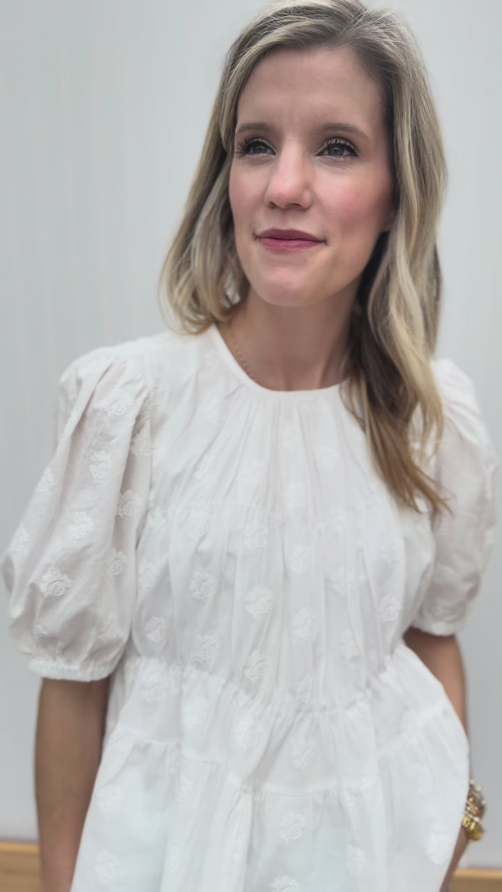 Video of Model wearing a white top with texturing, round neck, bubble short sleeves and pleating detail.