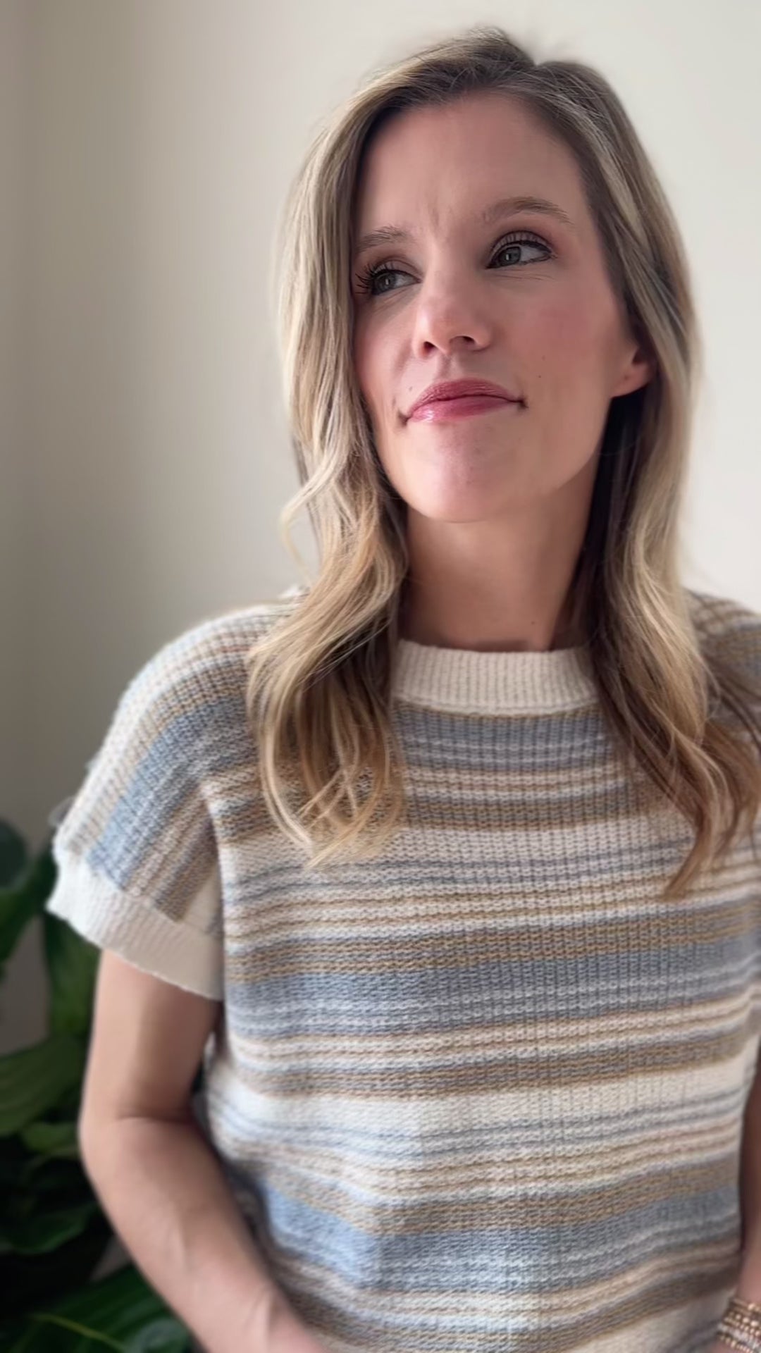 Video of Model wearing a cream sweater with taupe and blue stripes, short sleeves and ribbed detail.