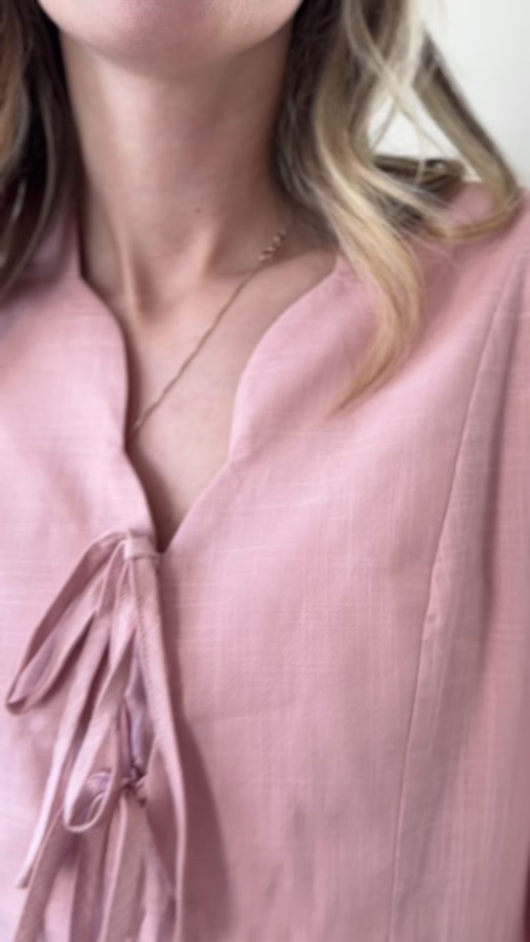 Video of Model wearing a blush midi with bubble sleeves, scalloped v-neck with tie and cinched waist. 