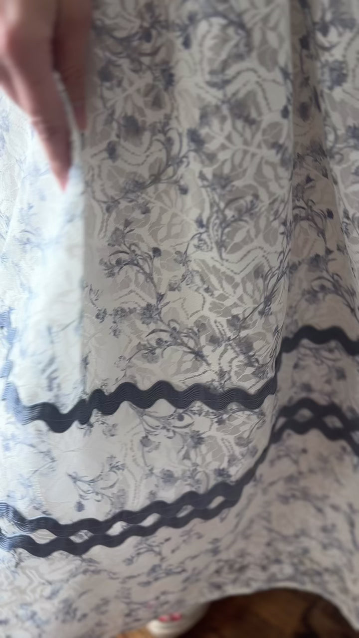 Video of Model wearing a cream midi with dusty blue floral and scalloping, square neck and short sleeves.