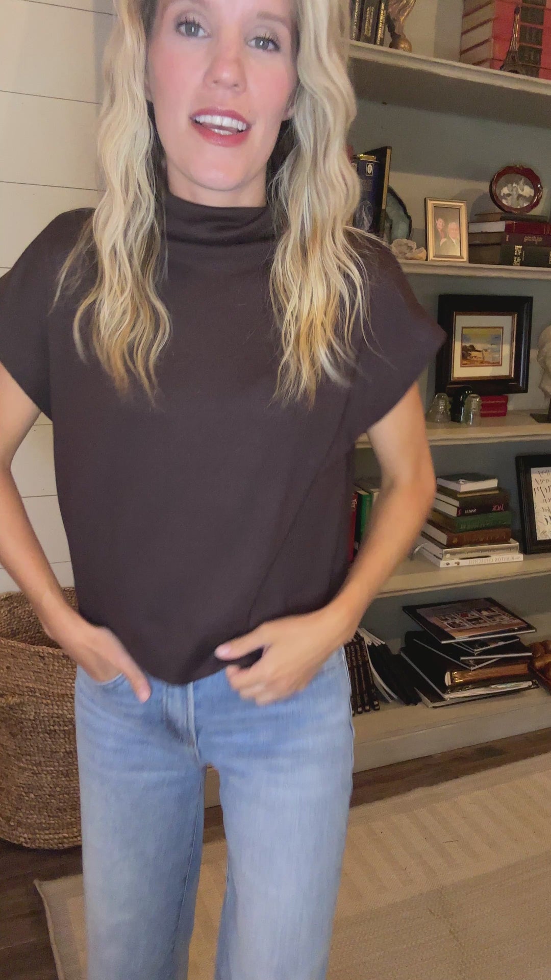 Video of Model wearing a mocha lightweight sweater with extended sleeves and a mock neck.  