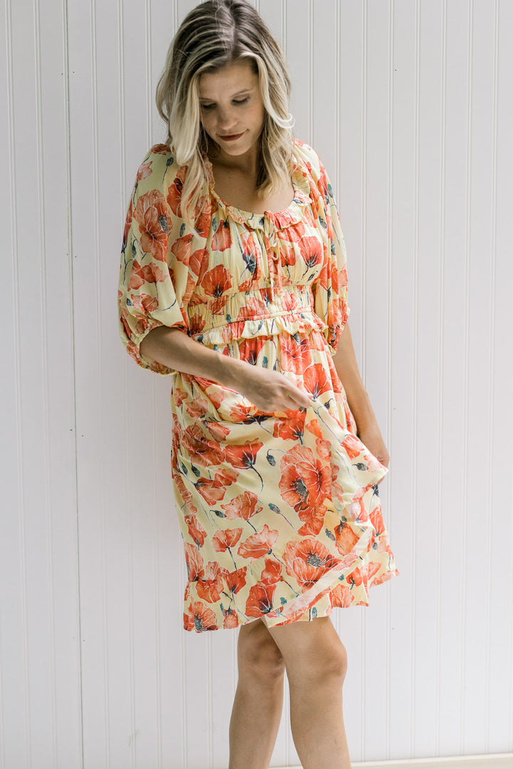 Model wearing a yellow above the knee dress with a coral floral pattern and a round neck.