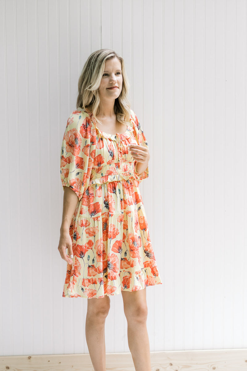Model wearing a yellow above the knee dress with a coral floral pattern and bubble quarter sleeves.