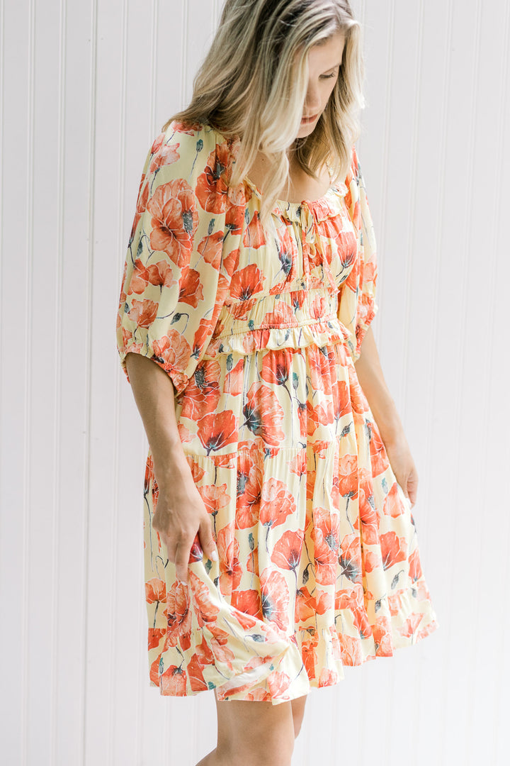 Model wearing a yellow dress with a coral floral pattern, an elastic waist and round neck.