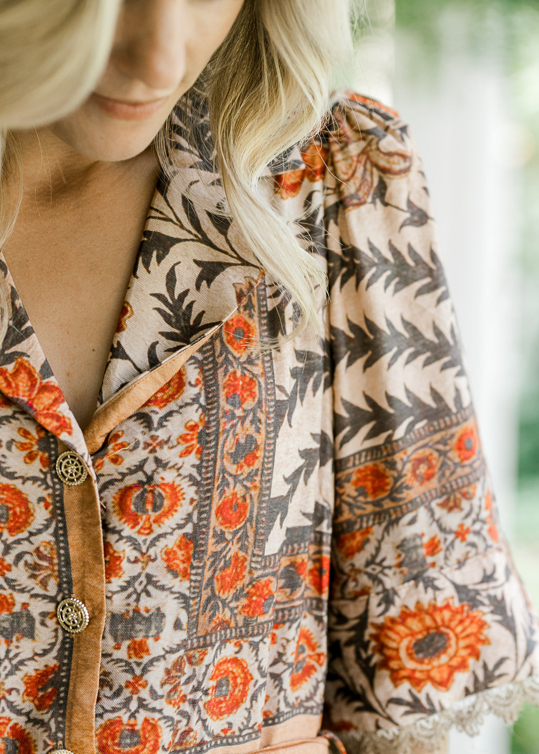 Close up of v-neck with a collar, pleated shoulder and buttons on a cream dress with floral. 