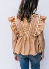 Back view of Model wearing a dusty orange top with ruffle cap sleeve and scallop white detail. 