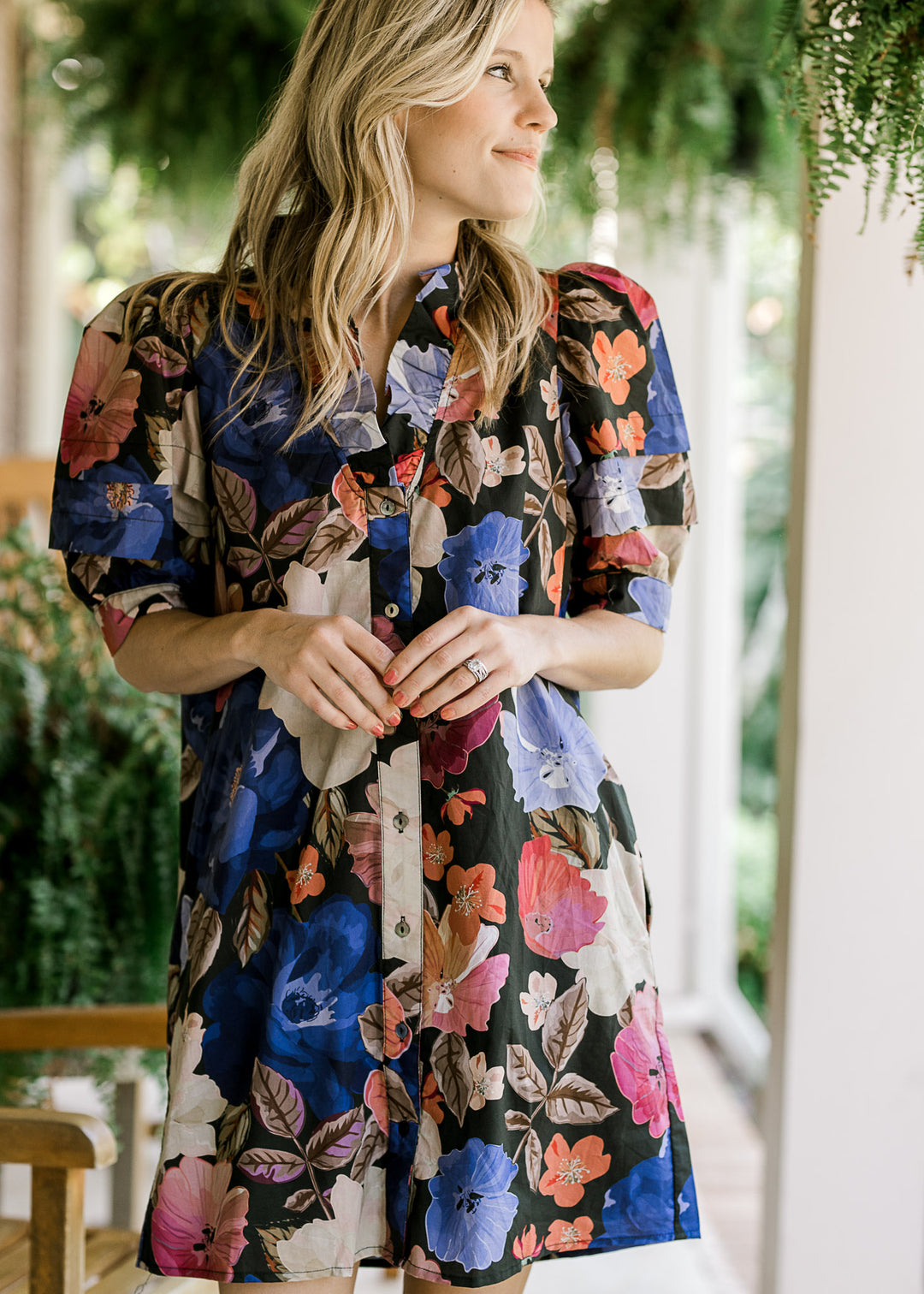 Model wearing an above the knee black dress with floral print, button front and puff short sleeves. 