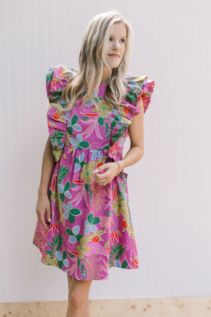 Model wearing a lilac dress with flowers, layered sleeveless top and a zip up back.