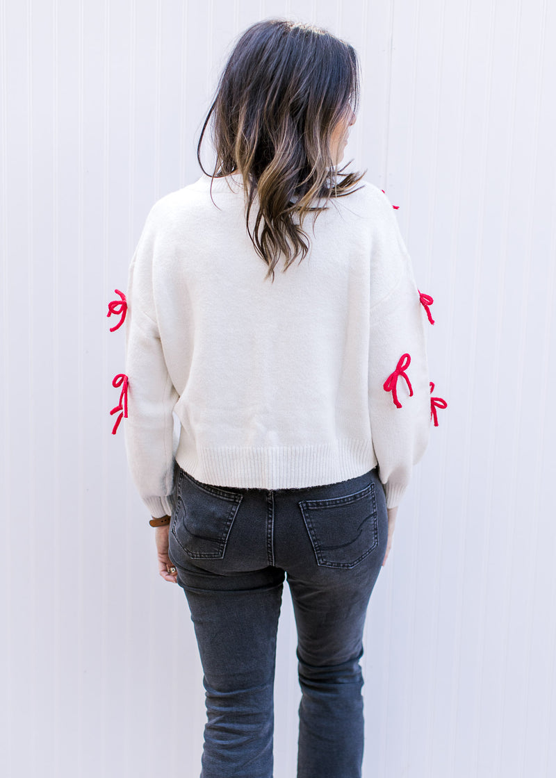 Back view of Model wearing a cream sweater with long sleeves and a round neck. 