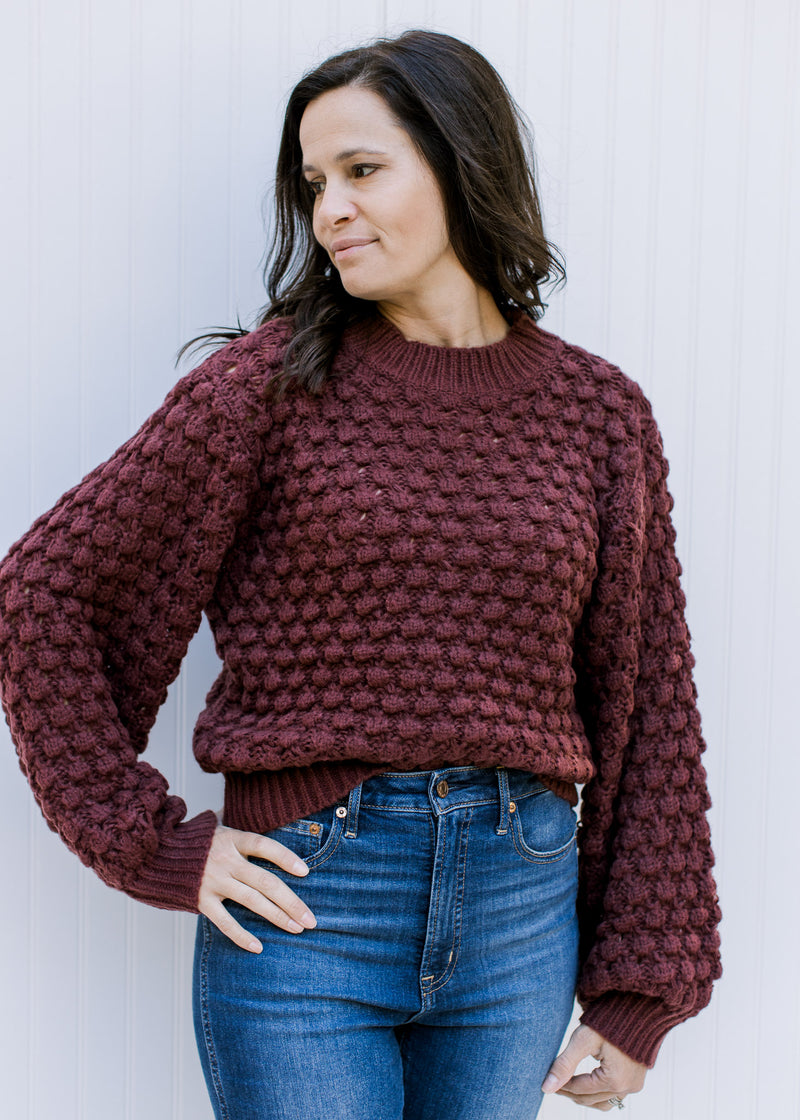 Model wearing a wine open knit sweater with bubble long sleeves, polyester material and round neck.