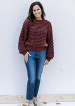 Model wearing jeans, mules and a wine open knit sweater with bubble long sleeves and a round neck.
