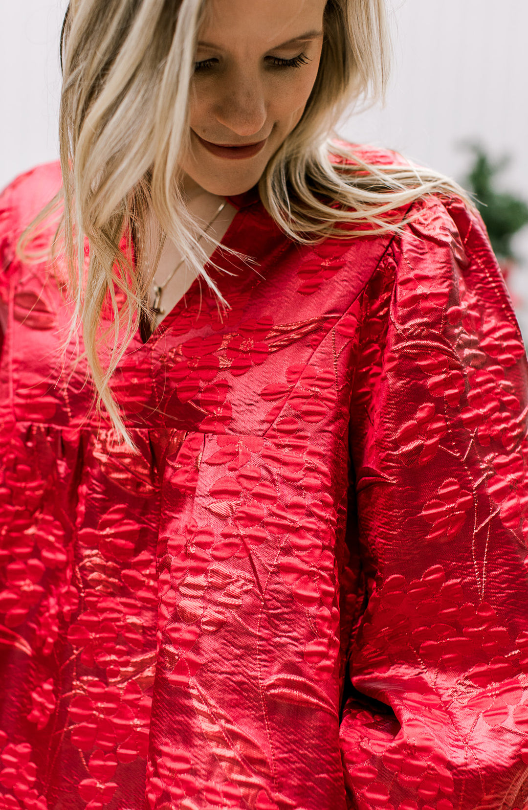 Close up of embossed floral shimmer on a bright red dress with a v-neck and bubble 3/4 sleeves. 