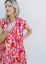 Close up view v-neck and ruffle cap sleeves on a cream v-neck dress with red and pink. 