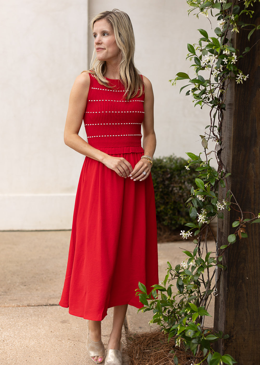 Model wearing heels and a red sleeveless midi with white stripes, smocked bodice and attached skirt.