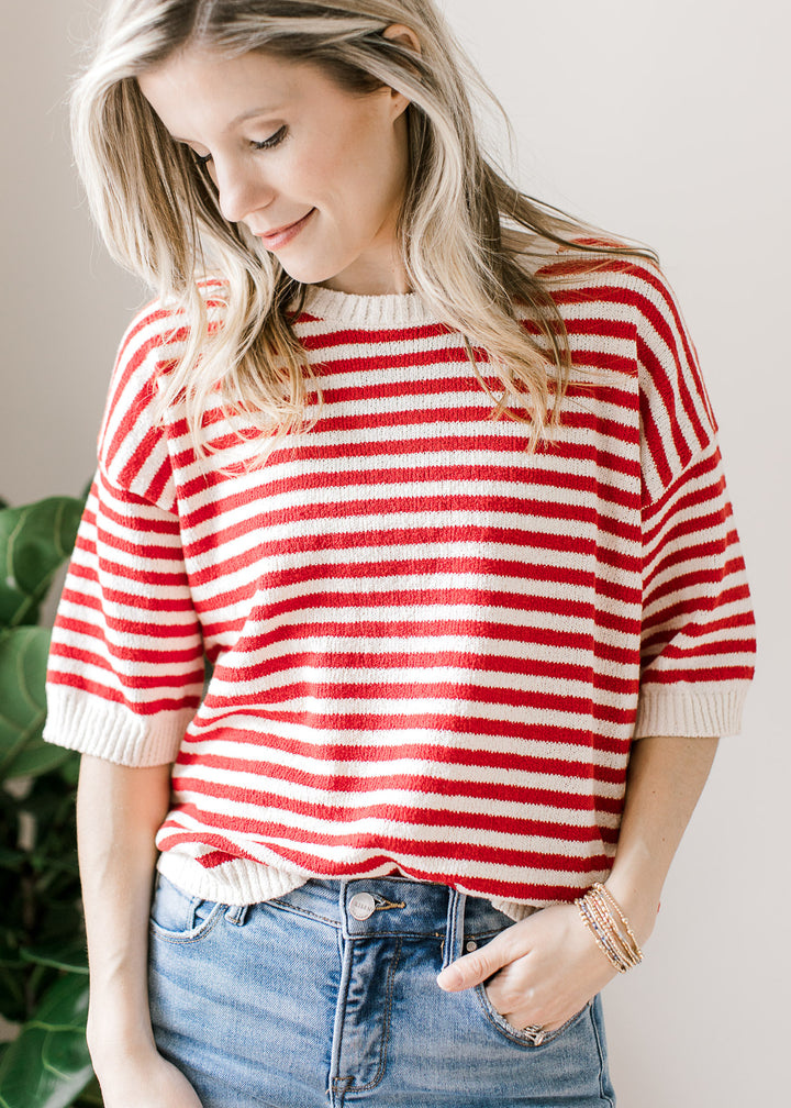 Model wearing a red and white striped knit sweater with short sleeves and button down the back. 