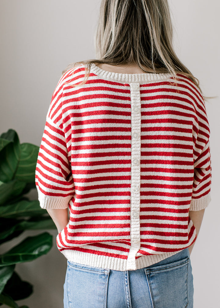 Back view of model wearing a red and white striped short sleeve sweater with button down back. 