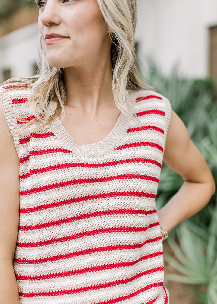 Model wearing a sleeveless red, cream, and white striped top with a knit material and round neck.