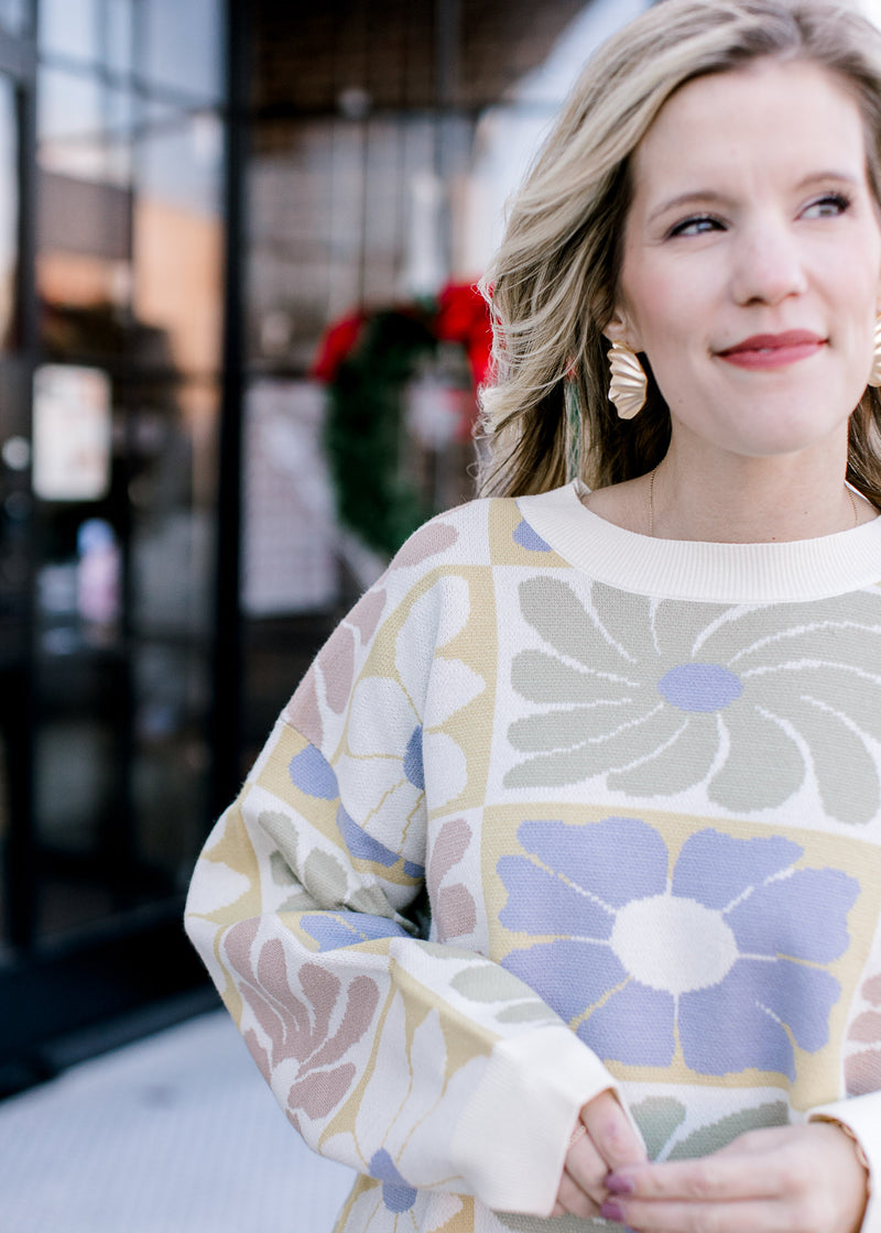 Close up of retro floral print on a cream sweater with a round neck, long sleeves and oversized fit.