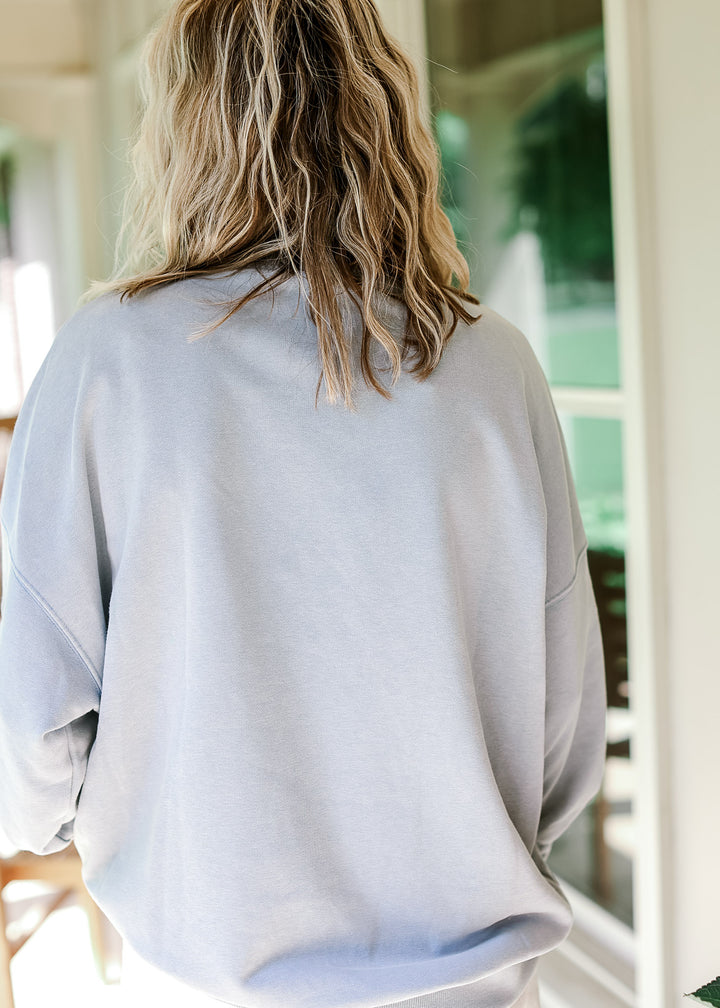 Back view of model wearing a pale blue lightweight sweatshirt with mock neckline and long sleeves.