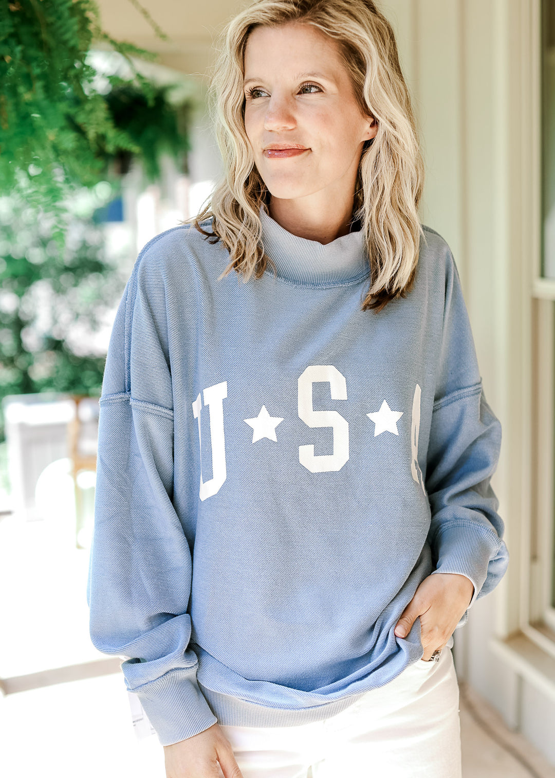 Model wearing a pale blue reversible sweatshirt with white "USA" graphic on front.